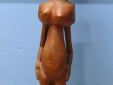 statue d'une femme debout sur un socle en bois, devant un mur bleu