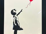 a black and white picture of a girl holding a red balloon