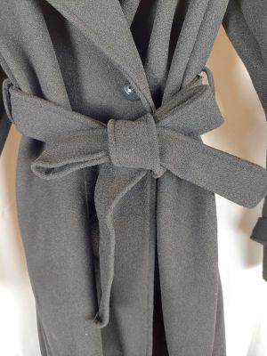 Le manteau est gris et est muni d'une ceinture