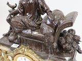 a bronze statue of a woman sitting on top of a clock