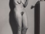 an old black and white photo of a naked woman leaning against a wall