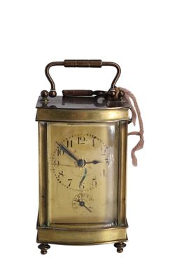 une petite horloge en laiton avec une corde autour de la poignée