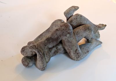 a sculpture of a dog laying on its back on a table