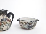 a small pitcher and a small bowl sitting next to each other