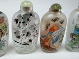 four glass vases with asian designs are lined up on a white surface