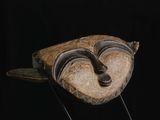 un masque en bois sur un support avec un fond noir