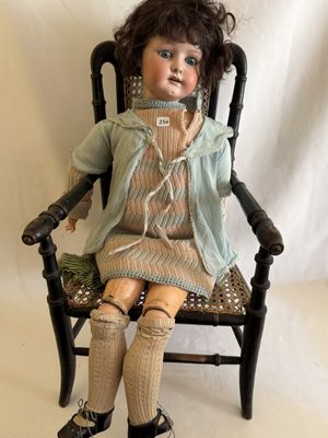 poupée assise sur une chaise devant un fond blanc