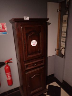 une grande armoire en bois surmontée d'un extincteur