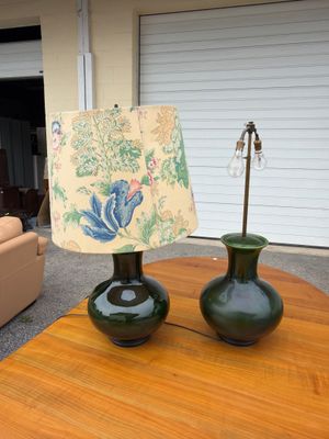 two green vases sitting on a table with a lamp on it