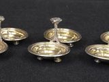six silver plated candlesticks with candles on them on a black surface