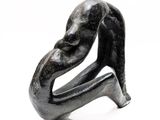 a black sculpture of a woman sitting on a chair