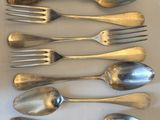 six cuillères et six fourchettes sont alignées sur une table
