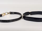 a pair of black leather bracelets with gold clasps