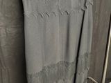a gray dress hanging on a rack in front of a curtain