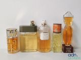 plusieurs types différents de flacons de parfum alignés sur une surface blanche