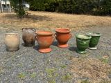 five different colored vases lined up on the ground
