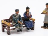 three figurines of people sitting on a bench
