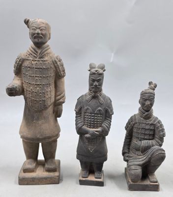 trois figurines en argile représentant un homme et une femme assis sur des blocs