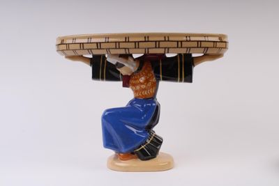 une figurine de femme portant un panier sur la tête