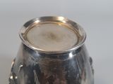 a silver vase with a bird on it sitting on a table
