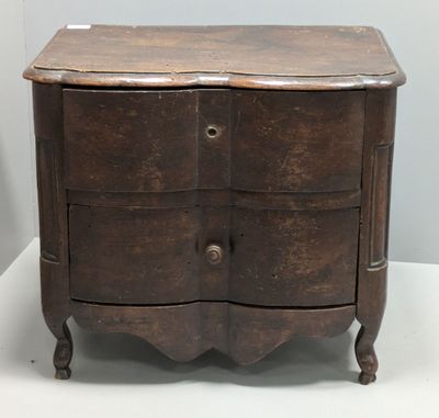 une petite commode en bois posée sur une surface blanche