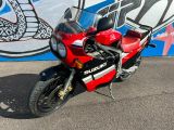 une moto rouge garée devant un mur couvert de graffitis