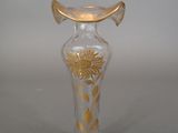 a glass vase that has a gold decoration on it