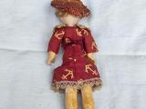 a small doll with a red dress and hat on a white sheet