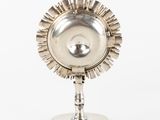 a small silver object on a stand on a white surface