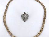 a close up of a gold chain with a heart charm on it