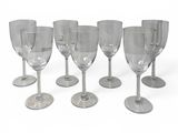 several empty wine glasses lined up in a row on a white surface