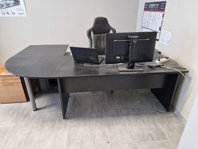 a desk with two computers and a chair in the corner