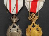 two medals are displayed on a black surface with a red and white ribbon