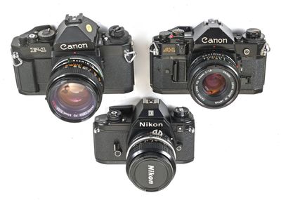 three black cameras are sitting next to each other on a white surface