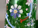 a green glass pitcher with a floral design on it
