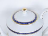 a white tea pot with a blue stripe on it