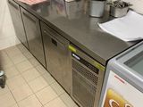 plan de travail en acier inoxydable dans une cuisine professionnelle équipée d'un réfrigérateur et d'un congélateur