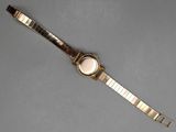 a close up of a watch on a table with a gray background