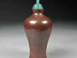 a brown vase with a green lid sitting on a white surface