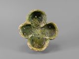 a close up of a green flower shaped object on a gray surface