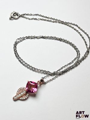 collier avec un cristal rose et une chaîne en argent sur fond blanc
