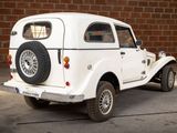 a small white car parked in front of a brick wall