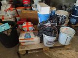 several buckets of paint are stacked on a pallet in a garage
