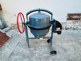 a cement mixer sitting on the concrete outside of a building