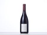 a bottle of red wine sitting on top of a white table