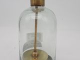 une petite bouteille en verre avec un socle en bois et une poignée dorée