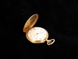 an old gold pocket watch sitting on a black surface