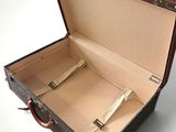 a brown suitcase with a handle that is open on a white surface