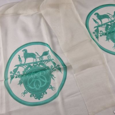 deux serviettes blanches ornées de motifs verts, posées sur une table