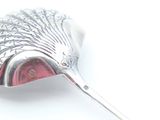 a silver spoon with a red handle on a white surface